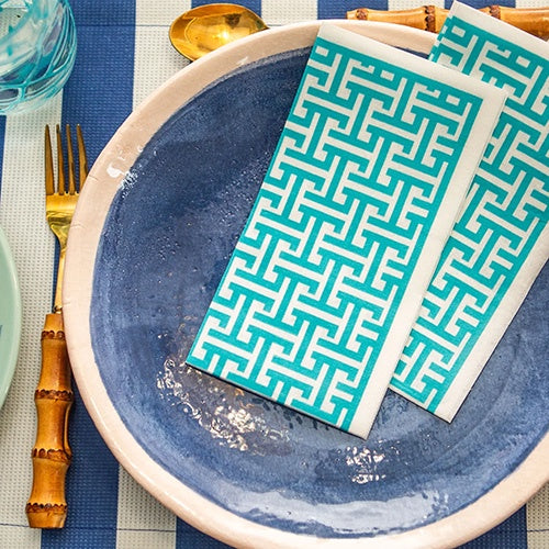 Turquoise patterned napkins on a blue plate with cutlery.