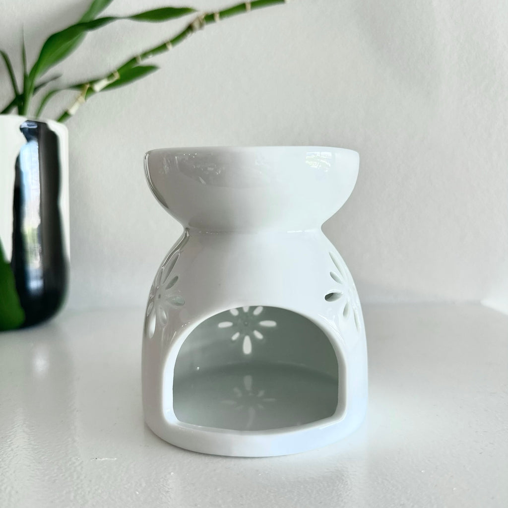 A white ceramic wax melt or essential oil burner with a floral pattern, designed for use with a lit tea candle.