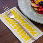 Load image into Gallery viewer, Silver fork on a yellow and white patterned napkin with a plate of fruit in the background.
