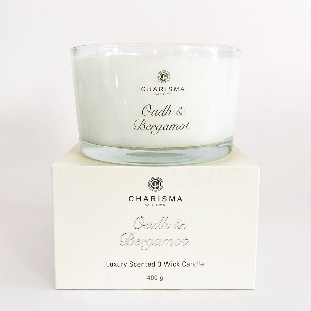 A clear glass candle with oudh and bergamot fragrance, labelled 'Charisma' and 'Luxury Scented 3 Wick Candle', presented on a branded box.