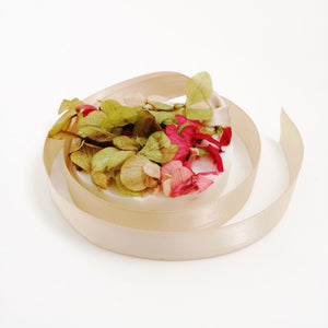 A beige wax tablet with pomegranate, bergamot, and patchouli scent, accompanied by dried petals, displayed on a white background.