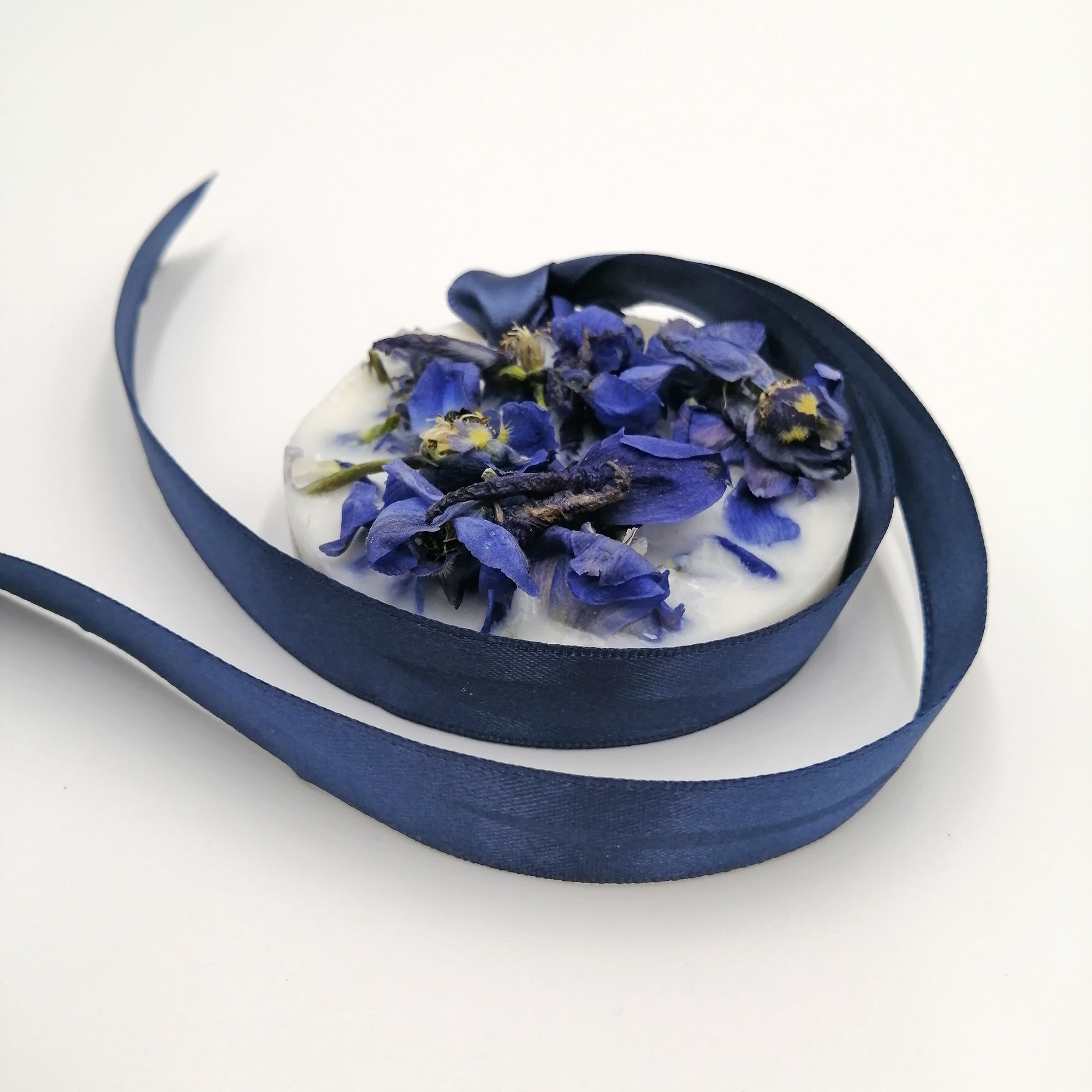 A scented wax tablet with a blue and purple floral design, surrounded by a swirl of blue ribbon.