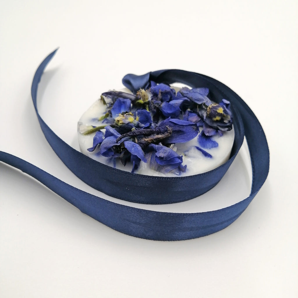 A scented wax tablet with a blue and purple floral design, surrounded by a swirl of blue ribbon.