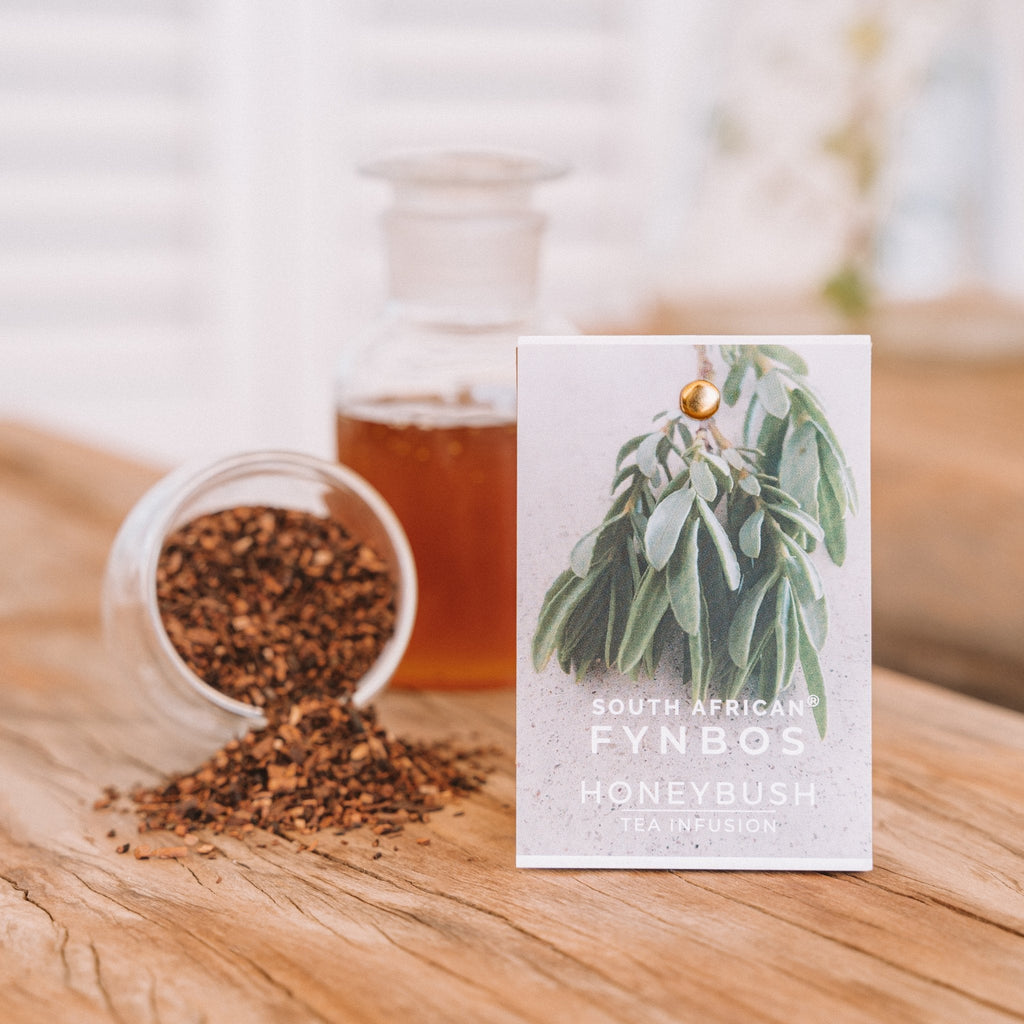 Product packaging for Fynbos Honeybush tea infusion, showcasing the box with an image of honeybush leaves and a glass jar of honey in the background.