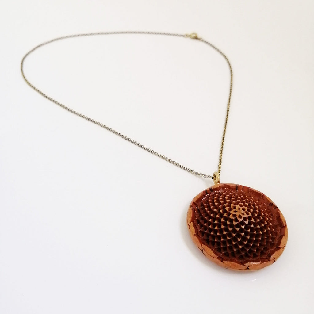 A brass chain necklace featuring a protea seed pod pendant.
