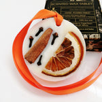Load image into Gallery viewer, Decorative wax tablet with citrus peel petals and an orange ribbon, with a box labeled &#39;Scented Wax Tablet Spicy Orange&#39; in the background.
