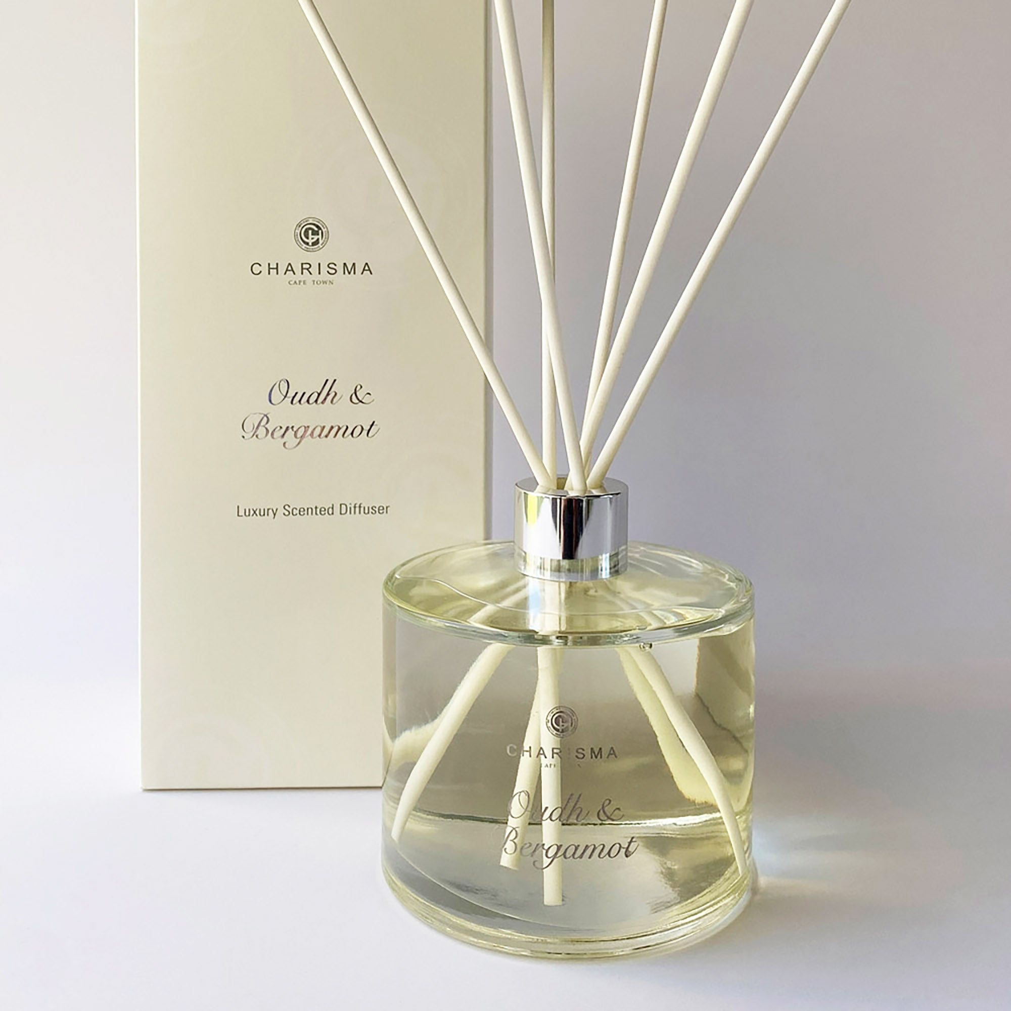 A clear glass diffuser bottle with oud and bergamot fragrance, featuring a label with the brand name Charisma Candles and the product name Oud & Bergamot - Luxury Scented Diffuser.