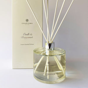 A clear glass diffuser bottle with oud and bergamot fragrance, featuring a label with the brand name Charisma Candles and the product name Oud & Bergamot - Luxury Scented Diffuser.