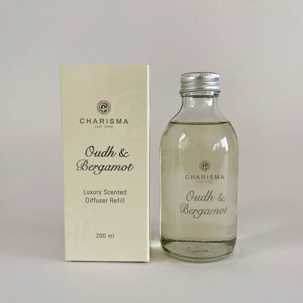 A glass bottle and a box packaging for a scented diffuser refill, with the label 'Oudh & Bergamot' and 'Luxurious Scented Diffuser Refill'.