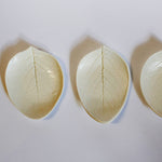Load image into Gallery viewer, A top down photograph of white porcelain soap dishes in the shape of leaves with the leaf veins and details pressed into the ceramic. 
