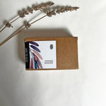 Load image into Gallery viewer, A bar of olive oil soap with oatmeal and lavender, accompanied by dried lavender buds, placed on a white background.
